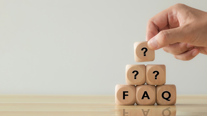 Holzwürfel mit 'FAQ' und Fragezeichen, symbolisiert häufig gestellte Fragen und Antworten für Kundeninformationen.
