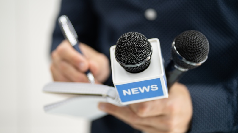 Nahaufnahme eines Reporters mit Mikrofonen und Notizblock – symbolisiert aktuelle News und Events rund um HAHN-Gasfedern.