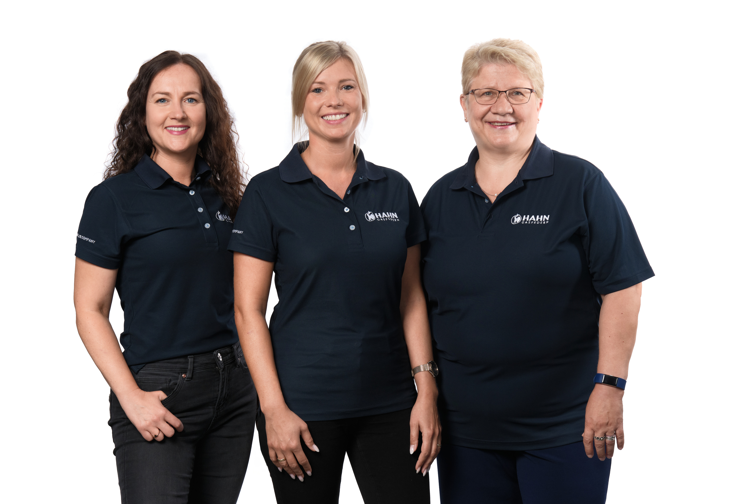 Das Personal-Team von Hahn Gasfedern in Firmenoberteilen lächeln vor neutralem Hintergrund – Team aus Service und Support.