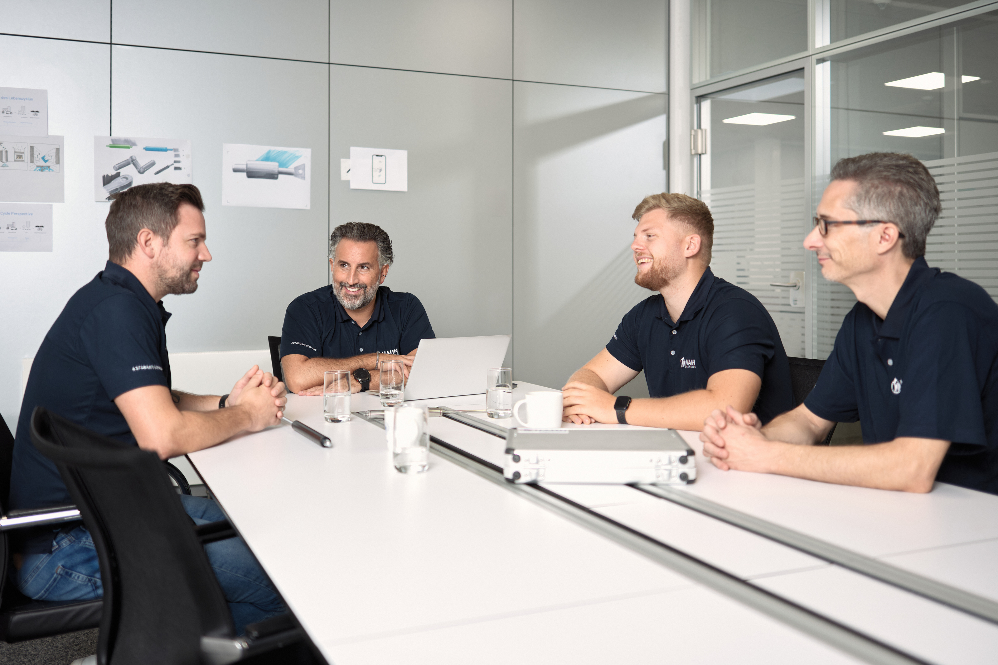 Teammeeting bei Hahn Gasfedern: Vier Mitarbeitende sitzen an einem Konferenztisch und besprechen technische Zeichnungen und Projekte. Teammeeting bei Hahn Gasfedern: Vier Mitarbeitende sitzen an einem Konferenztisch und besprechen technische Zeichnungen und Projekte.
